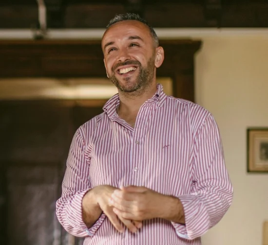 Pedro Daniel – Therapist Portrait Pedro Daniel smiling in a pink striped shirt