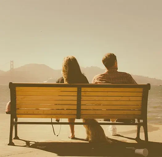 Two People Sitting Together Outdoors Two people sitting together on a bench in a peaceful outdoor setting